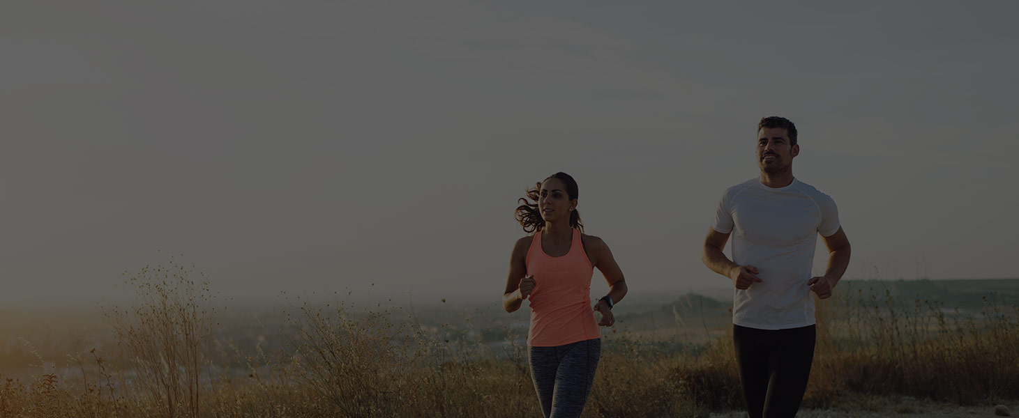 Two people running outdoors at sunset, active and well